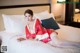 A woman in a red kimono laying on a bed.