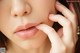 A close up of a woman's lips with her hand on her chin.