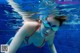 A woman in a bikini and goggles swimming in a pool.