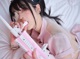 A woman laying on a bed holding a pink toy gun.