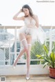 A woman in a white lingerie posing on a balcony.