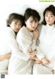 A group of three young women laying on top of a bed.