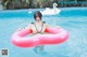 A woman in a bikini sitting on an inflatable ring in a pool.