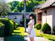 A woman in a white dress standing in front of a house.