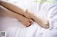 A woman's legs with a pair of ballet shoes on a bed.